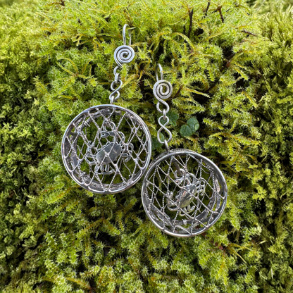 Crab pot shaped earrings with intricate filigree wire designs on a bright green moss background